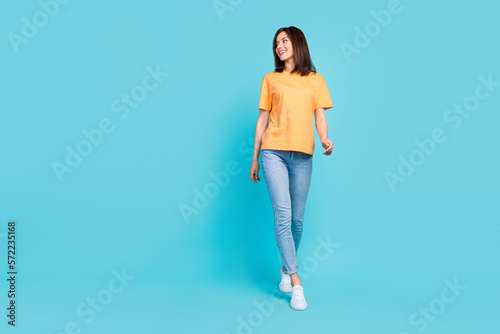 Full length portrait of stunning positive lady walking look empty space isolated on blue color background