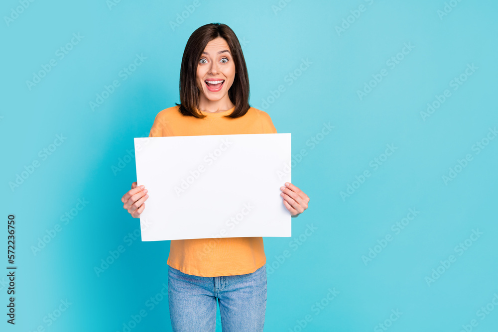 Photo of overjoyed funny positive girl straight hairdo dressed yellow t-shirt hold white placard isolated on turquoise color background Photo of overjoyed funny positive girl straight hairdo dressed yellow t-shirt hold white placard isolated on turquoise color background