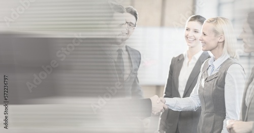 Composition of happy diverse business team shaking hands with motion blur