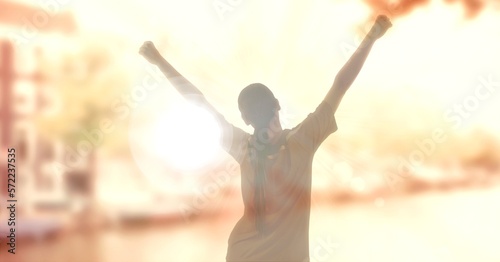 Composition of sports woman with arms in air celebrating over cityscape