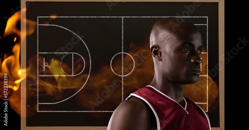 Composition of mixed race basketball player over basketball court with flames on black background