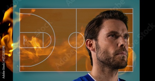 Composition of caucasian basketball player over basketball court with flames on black background