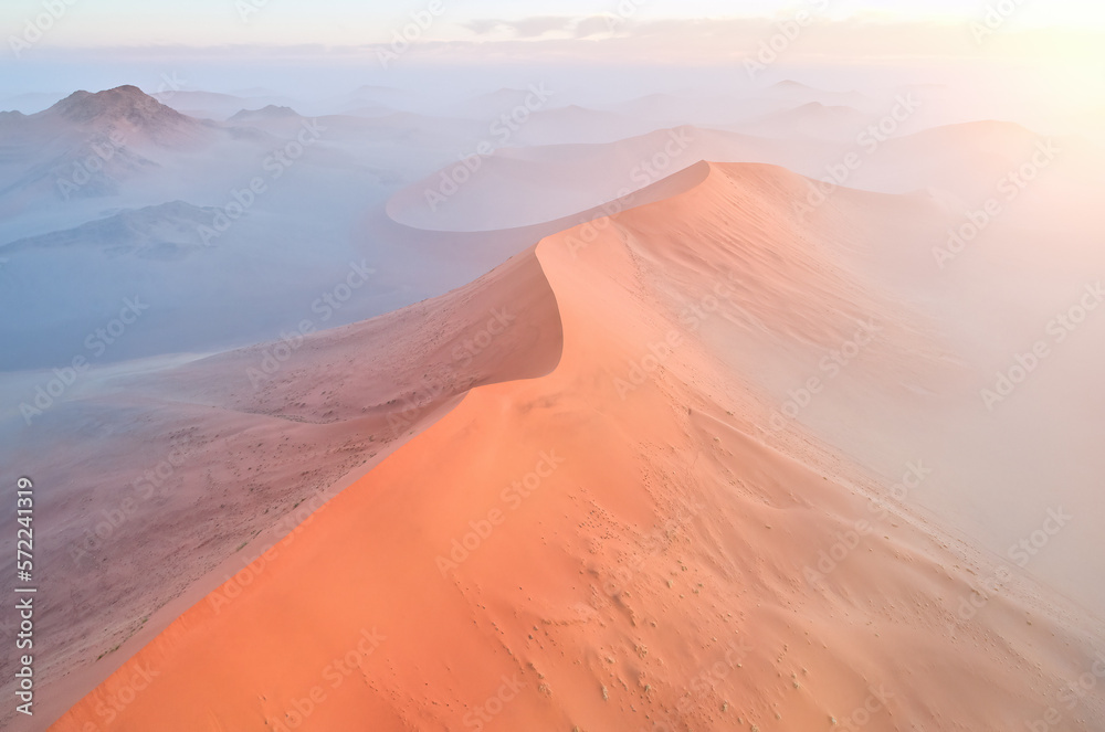 Orange Sand Dunes of the Namib Desert lit by sunrise: Aerial, panoramic photo of Sunrise over Desertscape of the Namib. Namib-Naukluft National Park, Namibia