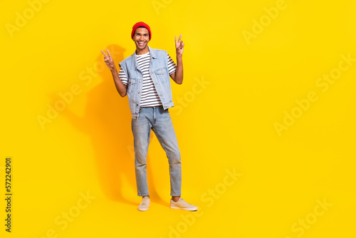 Full body photo of positive funny man demonstrate v-sign empty space isolated on yellow color background © deagreez