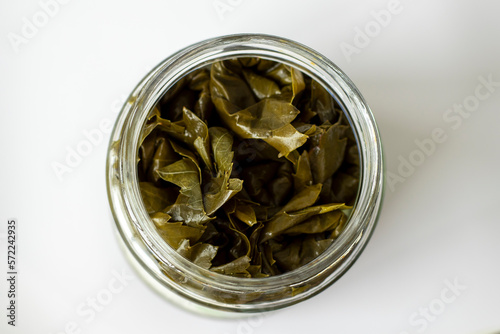 Pickled grape leaves twisted into rolls in a glass jar, top view.