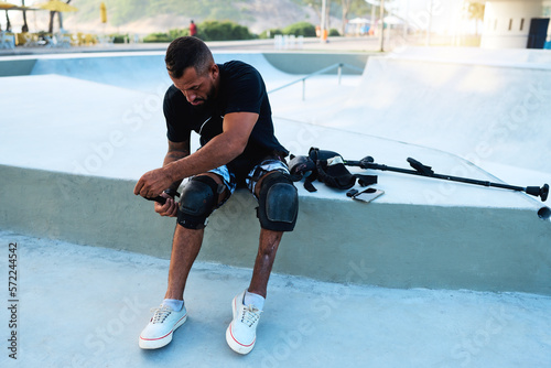mid adult brazilian man with leg disability prepares to skateboard photo