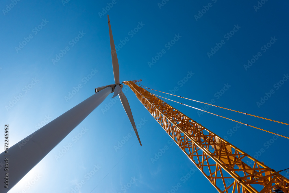 Installing a wind turbine in a windfarm. Maintenance in wind eolian energy with a crane that holds the propeller.