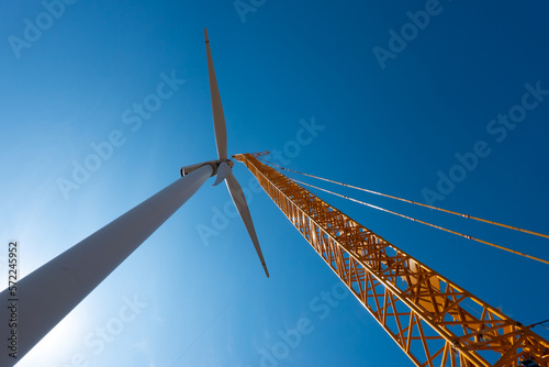 Obraz na płótnie Installing a wind turbine in a windfarm. Maintenance in wind eolian energy with a crane that holds the propeller. w salonie