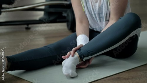 Young woman feels pain from an ankle injury while exercising at the gym.