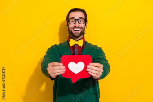 Photo of funny excited guy business developer wear green cardigan stylish bowtie hold red paper shape subscribe isolated on yellow color background