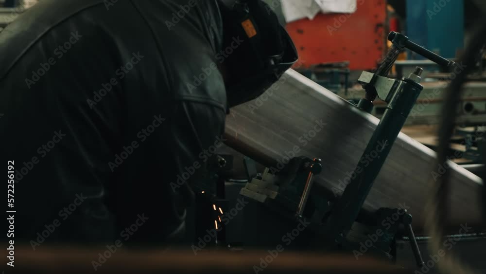 Close-up of a welder in a protective mask works with metal steel and iron with a welding machine in a factory, bright sparks and flashes in slow motion. Welding device Close-up of a welder in a protective mask works with metal steel and iron with a welding machine in a factory, bright sparks and flashes in slow motion. Welding device