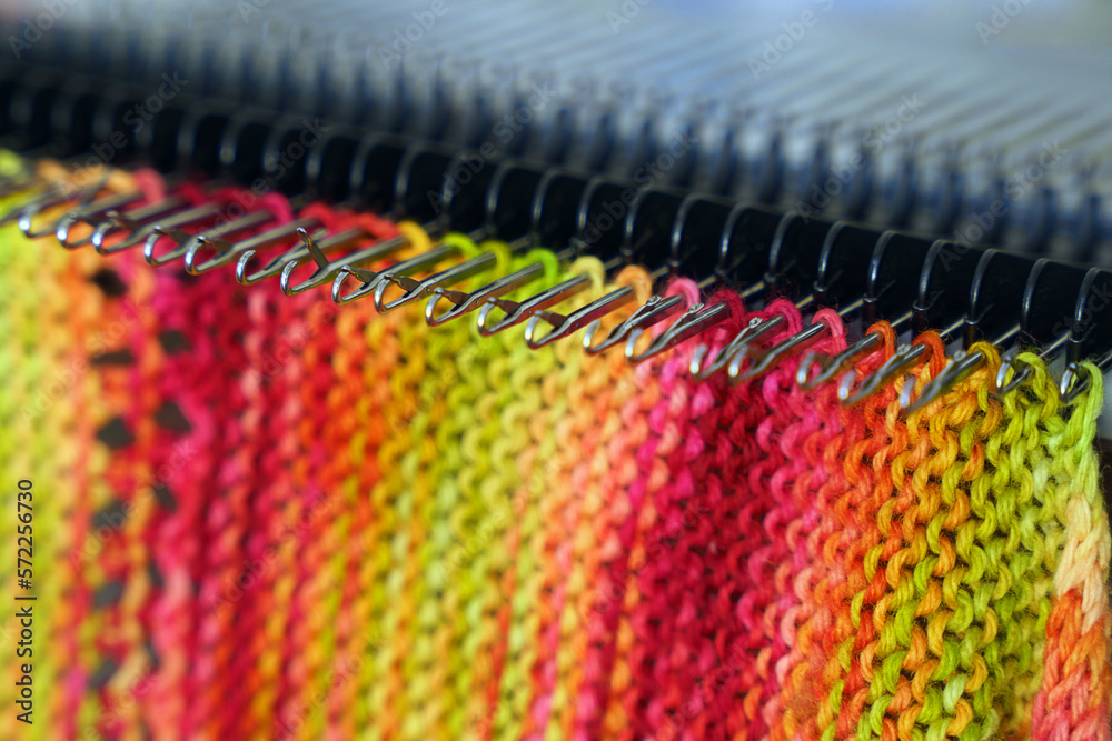 An openwork, colorful woolen scarf. Merino scarf on flatbed knitting