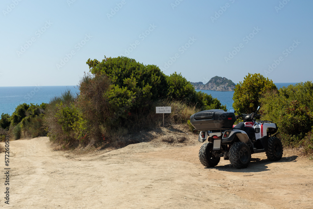 Fototapeta premium A quad parked above a picturesque beach, cliffside. Motorbike in a natural environment, no people.