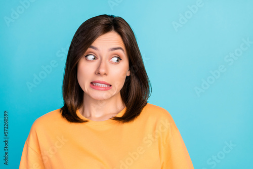 Portrait of nervous pretty lady grin teeth look interested empty space isolated on blue color background