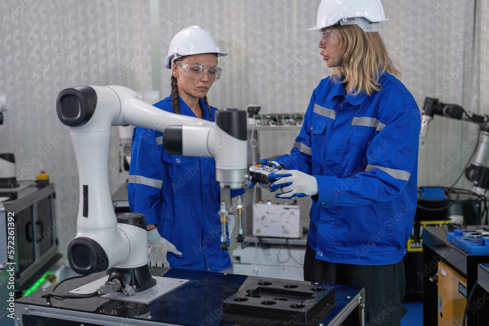 Female senior robotic engineer in modern factory teach new comer operate and maintenance robot arm Female senior robotic engineer in modern factory teach new comer operate and maintenance robot arm