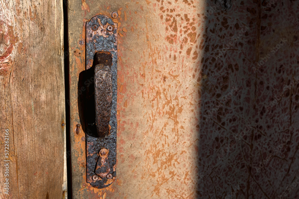 Rusty door handle and latch that is worn and broken.
