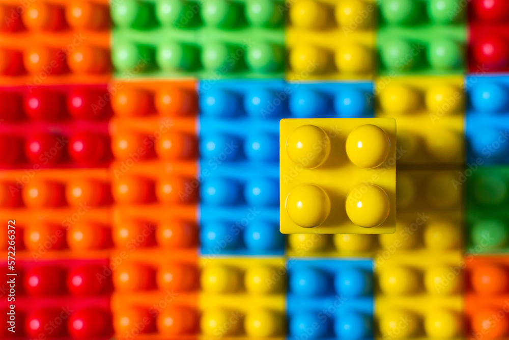 Naklejka premium Plastic building block pattern background with one block on top in focus.
