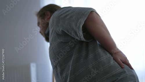 фотографія One overweight man having back pain by getting up from couch