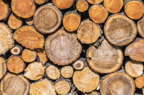 The background of a woodpile with firewood for heating the house in cold weather. Heating of the house. View of sawn wood for the fireplace. Firewood that needs to be chopped with an axe.