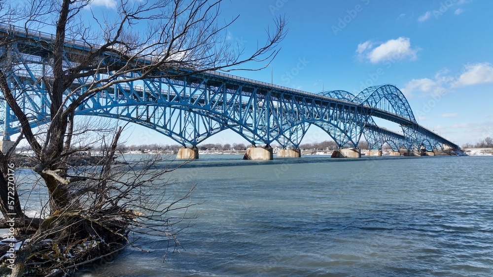 Obraz premium Beautiful South Grand Island Bridge crossing Niagara River with cars and trucks driving under blue sky and clouds 