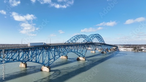 Beautiful South Grand Island Bridge crossing Niagara River with cars and trucks driving under blue sky and clouds  © Steve