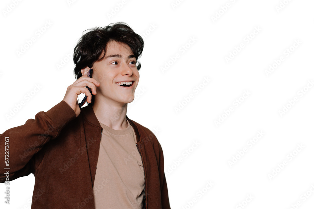 Amazed young handsome guy in beige t-shirt and brown jacket talks by phone toothy smiles looks aside standing against transparent background. Brunette boy isolated with copy space for ad. Mockup. Amazed young handsome guy in beige t-shirt and brown jacket talks by phone toothy smiles looks aside standing against transparent background. Brunette boy isolated with copy space for ad. Mockup.