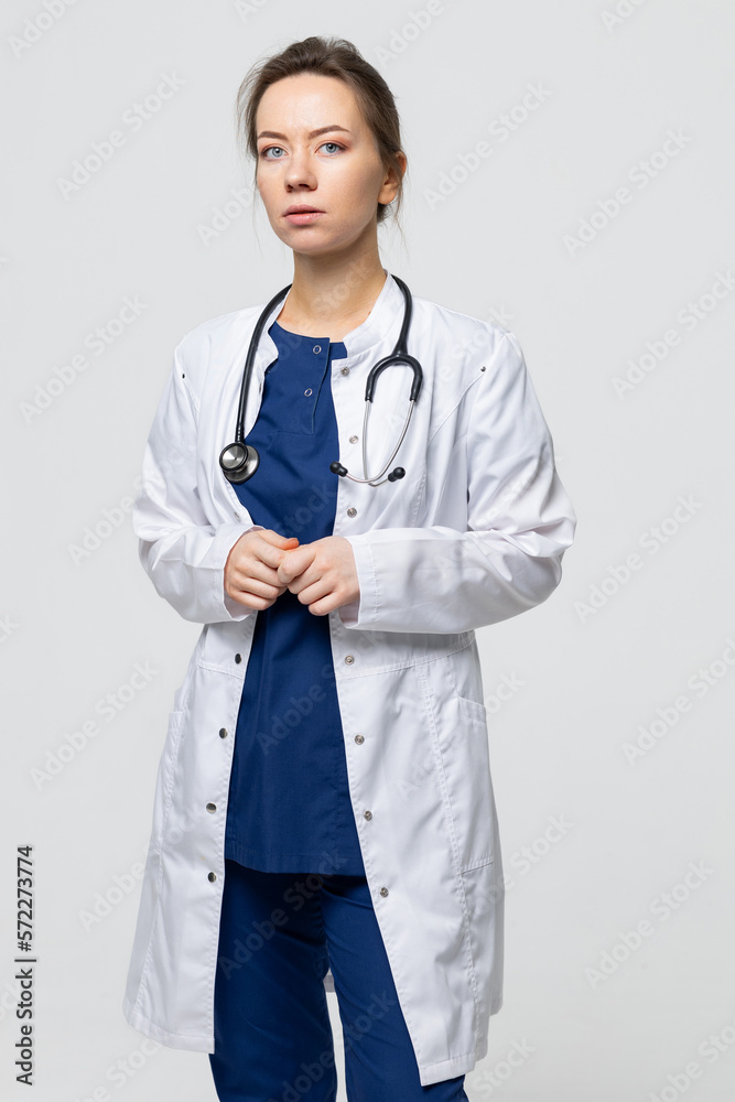 A thoughtful doctor looks into the camera. Female therapist in a white coat A thoughtful doctor looks into the camera. Female therapist in a white coat