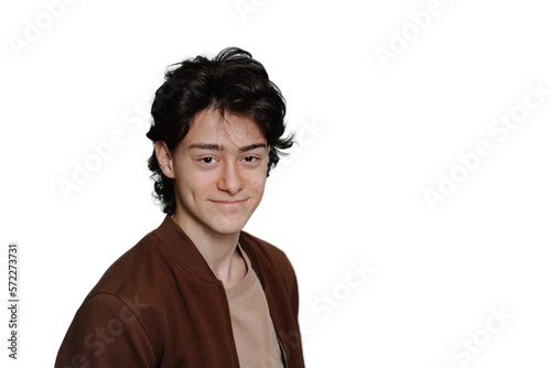 Portrait of confident caucasian schoolboy in brown jacket smiles looks at camera stands against turquoise backdrop with copy space. Handsome Italian guy satisfied, purposeful, mockup. Happy teen.