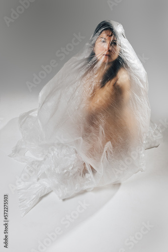 Woman wrapped in polyethylene sitting on floor