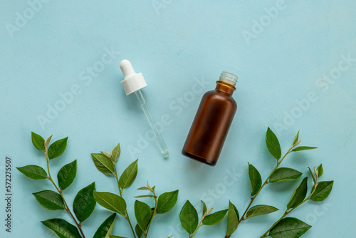Tea tree essential oil in dropper bottle. Herbs cosmetic background