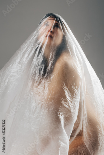 Woman wrapped in polyethylene sitting on floor