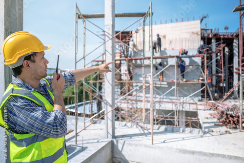 Civil engineer or supervisor inspects and directs workers on a building construction site.