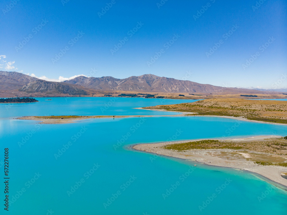 An aerial view of the blue glacial lake - Lake Tekapo, with mountains  and blue sky backgrounds, in South Island, New Zealand