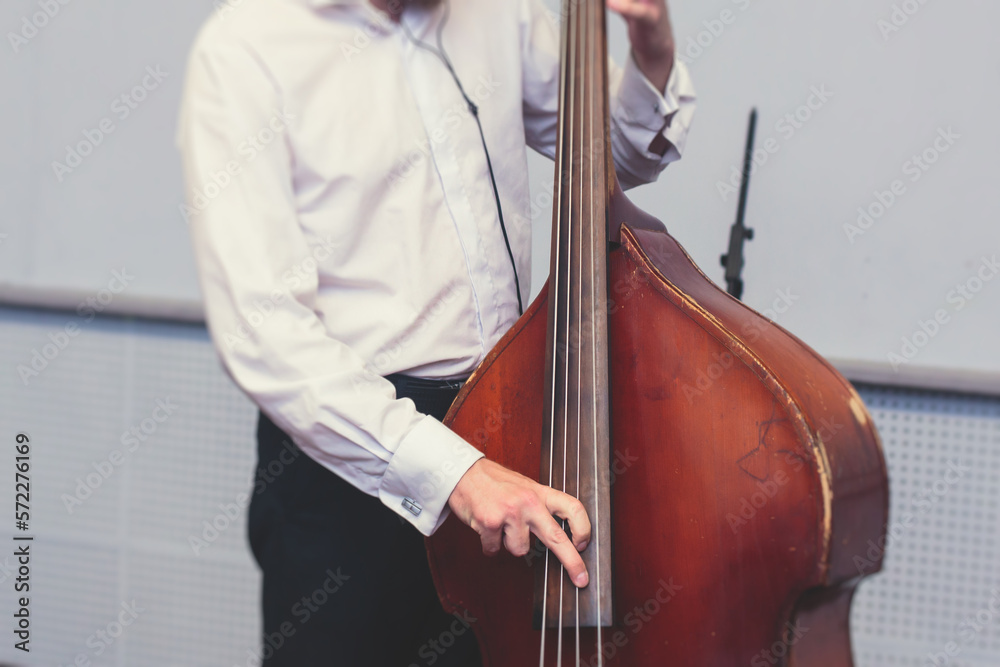 Contrabass cellist player in headphones during rehearsal, recording sound for new album song at studio, cello violoncellist musician with microphone and musical band orchestra, music production Contrabass cellist player in headphones during rehearsal, recording sound for new album song at studio, cello violoncellist musician with microphone and musical band orchestra, music production