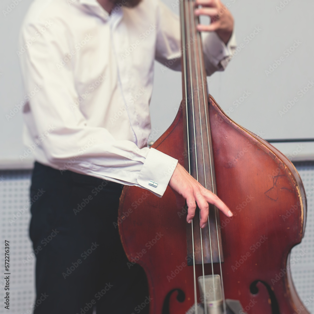 Contrabass cellist player in headphones during rehearsal, recording sound for new album song at studio, cello violoncellist musician with microphone and musical band orchestra, music production Contrabass cellist player in headphones during rehearsal, recording sound for new album song at studio, cello violoncellist musician with microphone and musical band orchestra, music production