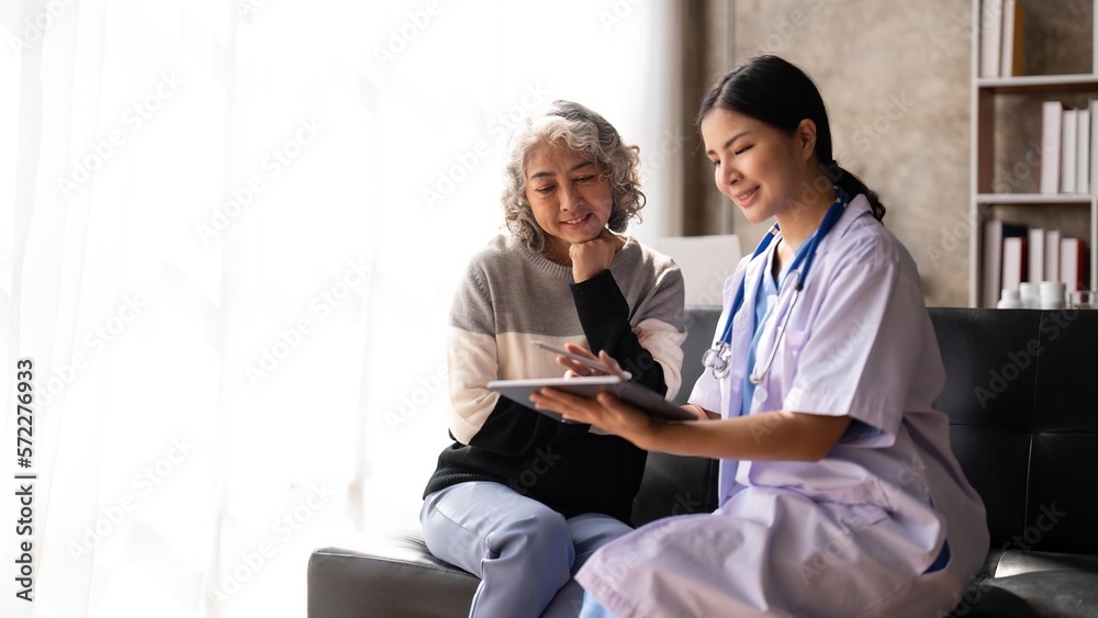 Fototapeta premium Nurse talking with a nursing home patient about his health. The nurse is making notes on a digital tablet