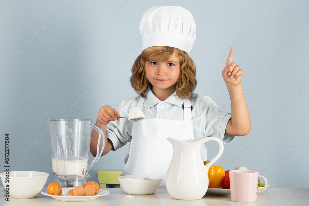 Cooking children. Chef kid boy making food with flour. Portrait of little child in form of cook isolated on grey background. Kid chef. Cooking process. Cooking children. Chef kid boy making food with flour. Portrait of little child in form of cook isolated on grey background. Kid chef. Cooking process.