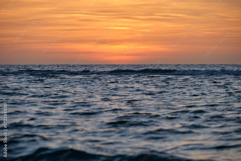 Fototapeta premium Dramatic red ocean waves at sunset with soft evening sea dark water