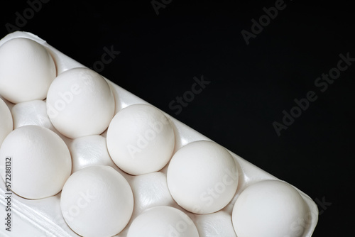 Tray with white chicken eggs on a dark background