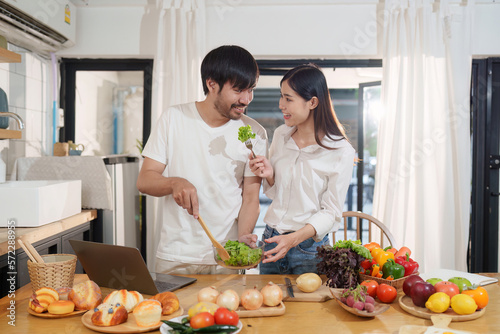 Young happy asian couple preparing healthy meal in kitchen at home. Food and healthy lifestyle concept.