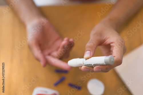 young woman using blood test kit at home while doing health check . home finger prick blood test . close up, diabetes concept, elderly health care,