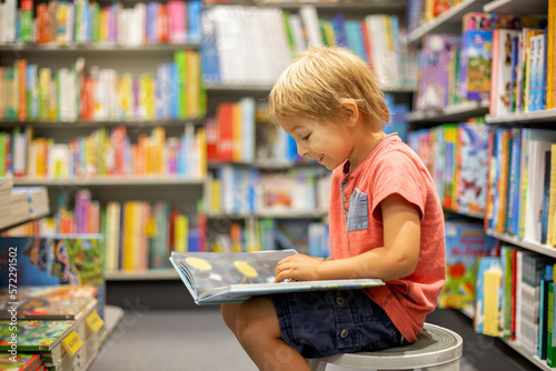 Cute preschool child, looking at books in a bookstore on summer day