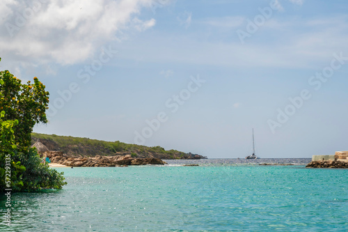 View of the ocean, from the shore of Curacao, a Caribbean island in the Dutch Antilles. A sailing boat can be seen just of the coast.