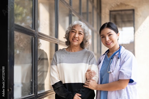 Young caregiver helping senior woman walking. Nurse assisting her old woman patient at nursing home. Senior woman with walking stick being helped by nurse at home.