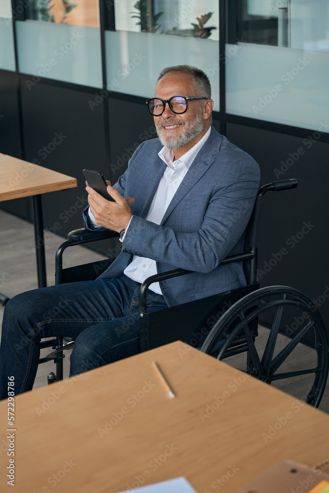 Optimistic middle-aged man in wheelchair with phone in his hands