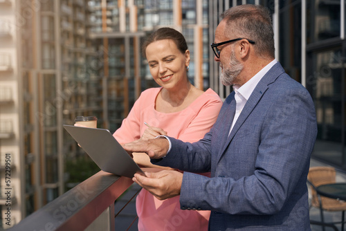 Businessman in business clothes shows something in laptop to attractive woman photo