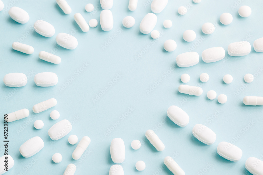 Scattered white pills on blue table. Mock up for special offers as advertising, web background or other ideas. Medical, pharmacy and healthcare concept. Copy space. Empty place for text or logo