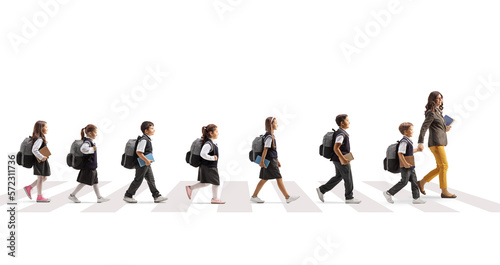 Teacher crossing road on a pedestrian crossing with schoolchildren in a row