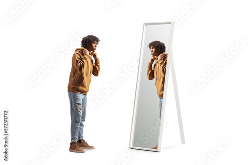 Full length profile shot of an african american young man standing in front of a mirror photo