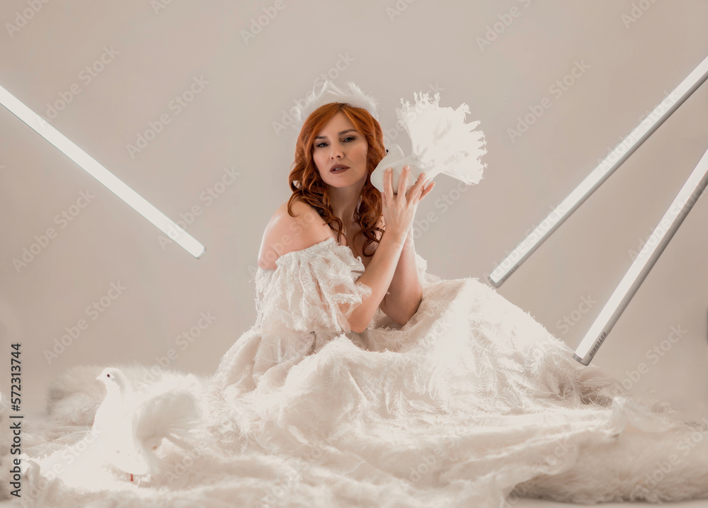 Naklejka premium portrait of a girl in a white dress with a dove in her hands